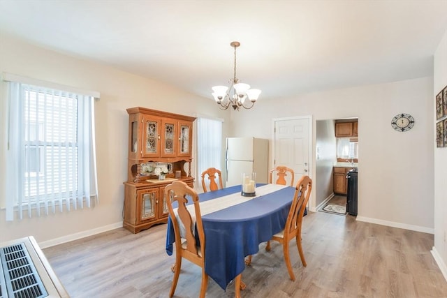 dining space with an inviting chandelier, light wood-style floors, and baseboards