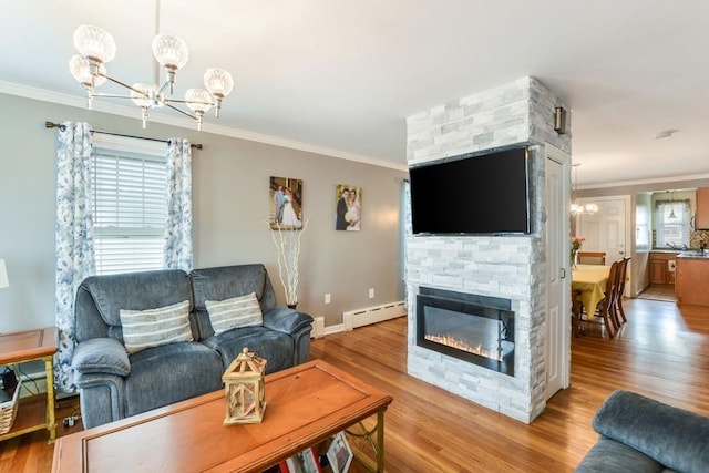 living area with a notable chandelier, light wood-style floors, baseboard heating, and ornamental molding