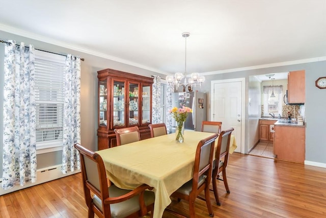 dining space with light wood-style floors, baseboard heating, a chandelier, and crown molding