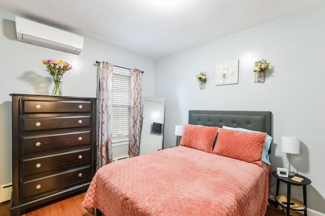 bedroom featuring a baseboard heating unit, wood finished floors, and a wall unit AC