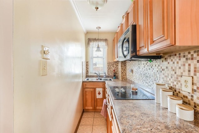 kitchen featuring ornamental molding, a sink, stainless steel microwave, tasteful backsplash, and black electric stovetop