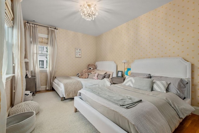 bedroom with a chandelier, wood finished floors, wallpapered walls, and baseboards