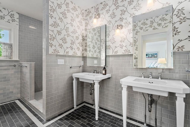 full bath with wallpapered walls, a wainscoted wall, walk in shower, tile walls, and tile patterned floors