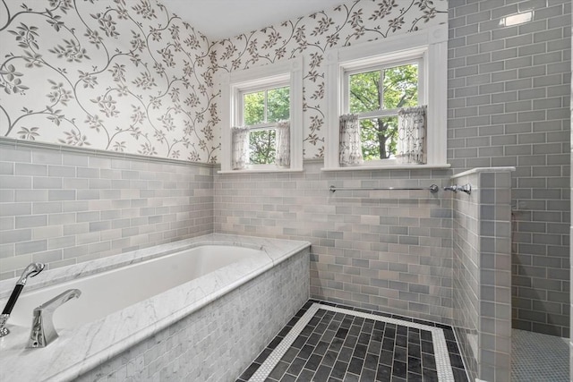 bathroom featuring wallpapered walls, tile walls, a garden tub, tile patterned flooring, and wainscoting