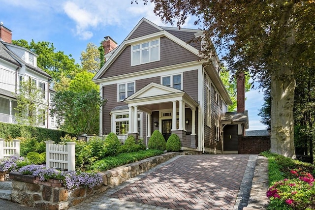 view of front of home with a chimney, covered porch, and fence