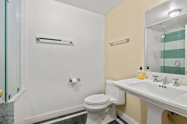 bathroom featuring baseboards, a shower stall, toilet, a sink, and tile patterned flooring