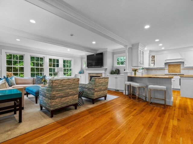 living room featuring ornamental molding, light wood finished floors, healthy amount of natural light, recessed lighting, and a fireplace