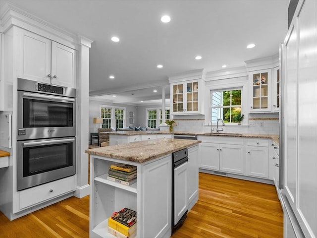 kitchen with double oven, a sink, light wood-style floors, recessed lighting, and decorative backsplash