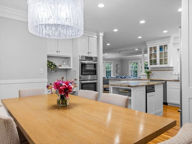 dining space featuring ornamental molding, recessed lighting, light wood-style flooring, and a wainscoted wall