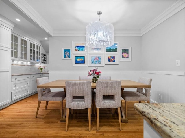 dining room featuring ornamental molding, light wood finished floors, wainscoting, recessed lighting, and a chandelier