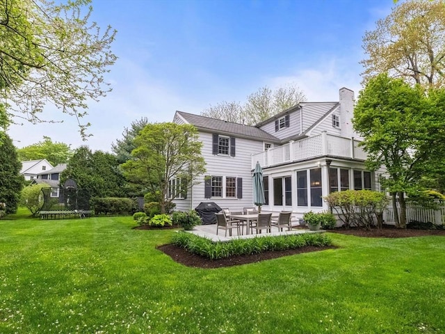 back of property with a balcony, a patio area, and a chimney