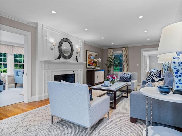 living area with wood finished floors, a fireplace, healthy amount of natural light, ornamental molding, and recessed lighting
