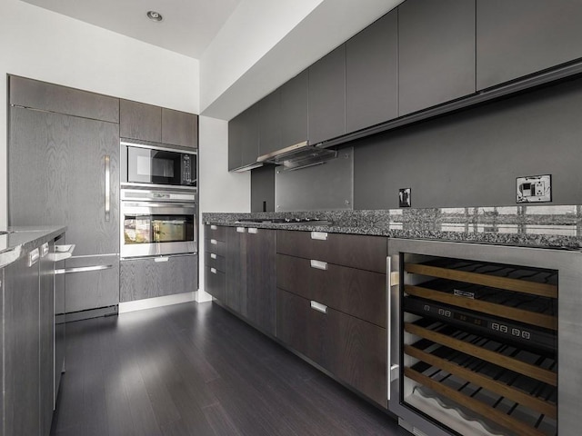 kitchen with beverage cooler, dark stone counters, dark wood-type flooring, black appliances, and dark brown cabinets