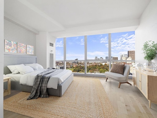 bedroom with light hardwood / wood-style flooring and a wall of windows