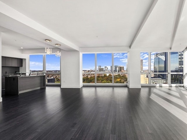 unfurnished living room featuring dark hardwood / wood-style floors, a chandelier, and beam ceiling