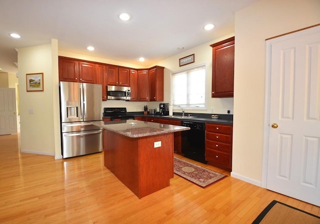 kitchen featuring light wood finished floors, recessed lighting, black appliances, dark brown cabinets, and a center island