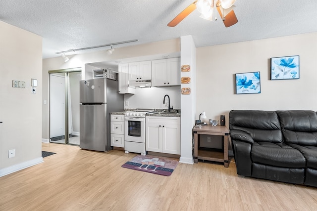 kitchen with light wood-type flooring, a textured ceiling, white range oven, white cabinets, and stainless steel refrigerator