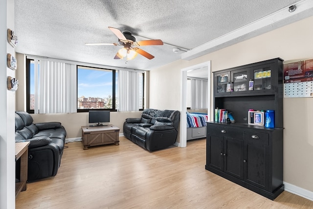 living room with ceiling fan, light hardwood / wood-style floors, and a textured ceiling