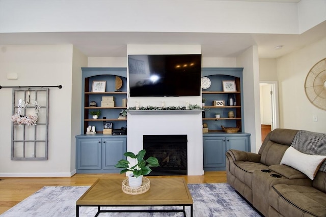 living room with a fireplace, baseboards, and light wood-style floors