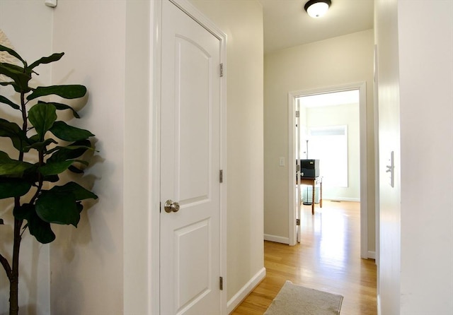 corridor featuring light wood finished floors and baseboards