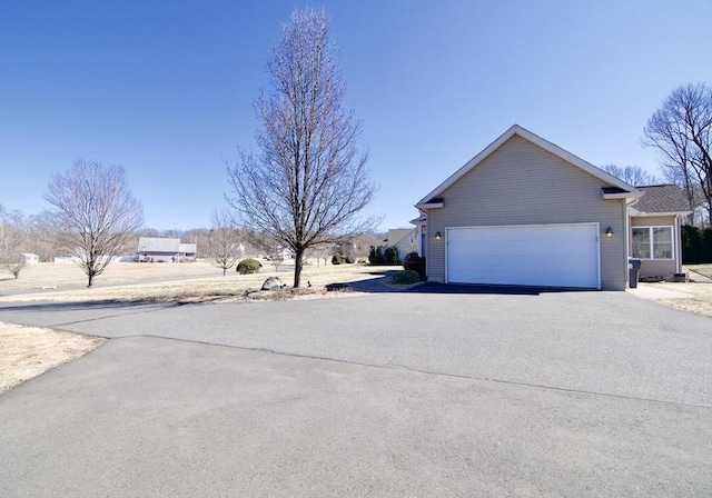 view of property exterior featuring an attached garage and driveway