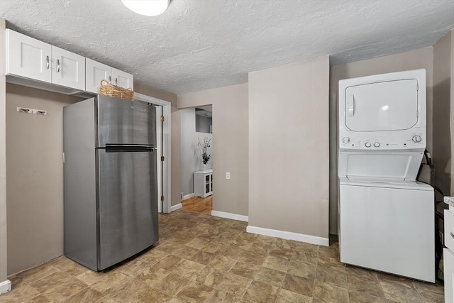 12 Allen Ct Unit 12, Northborough, MA 01532 - kitchen featuring freestanding refrigerator, estacked washer and dryer, white cabinets, stone finish floors, and baseboards