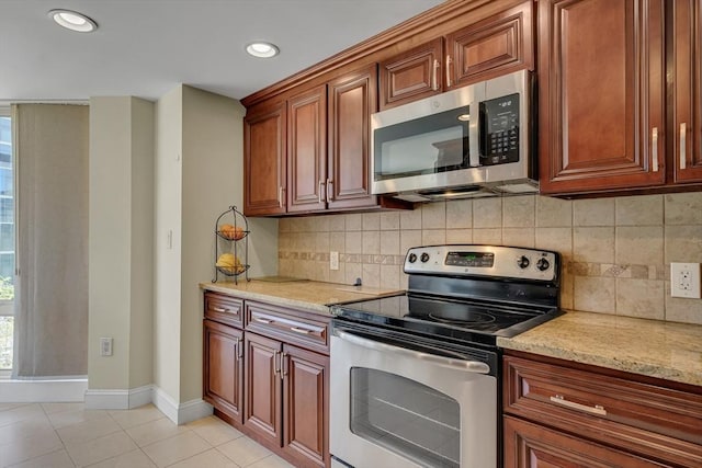 75-83 Cambridge Pkwy Unit W403, Cambridge, MA 02142 - kitchen with appliances with stainless steel finishes, light tile patterned floors, baseboards, backsplash, and light stone countertops