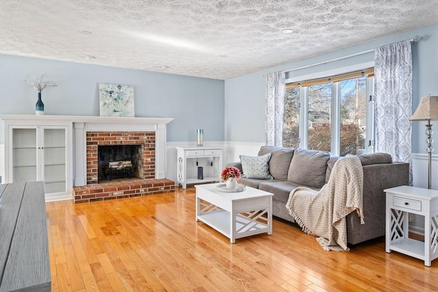 living room with a brick fireplace, hardwood / wood-style floors, and a textured ceiling