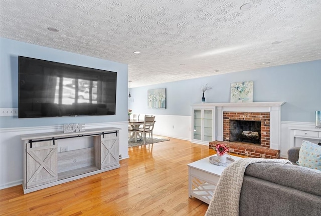 living room with hardwood / wood-style floors, a textured ceiling, and a fireplace