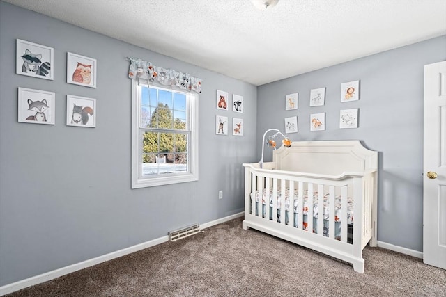 carpeted bedroom with a textured ceiling and a crib