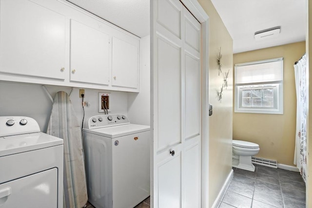 washroom featuring cabinets, light tile patterned floors, and washer and clothes dryer