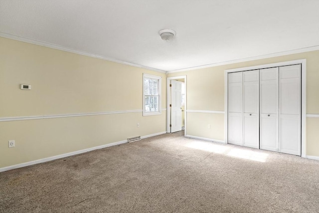 unfurnished bedroom featuring crown molding, a closet, and carpet