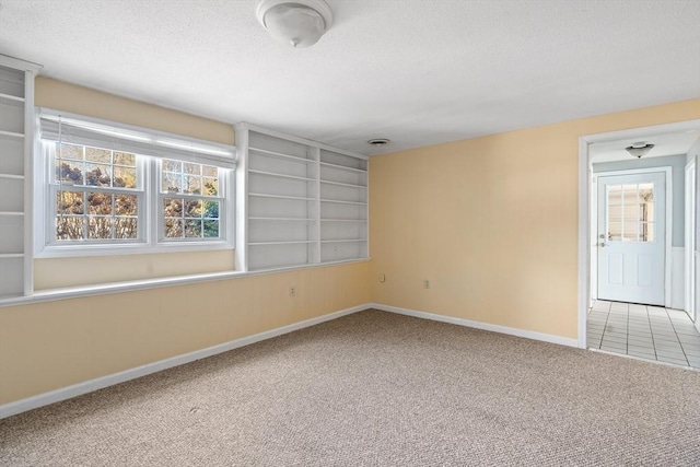 carpeted empty room featuring built in features and a textured ceiling