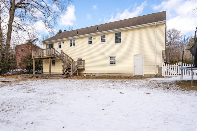 snow covered property with a trampoline and a deck