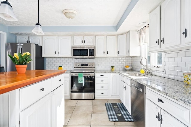 kitchen featuring white cabinetry, sink, decorative light fixtures, and appliances with stainless steel finishes