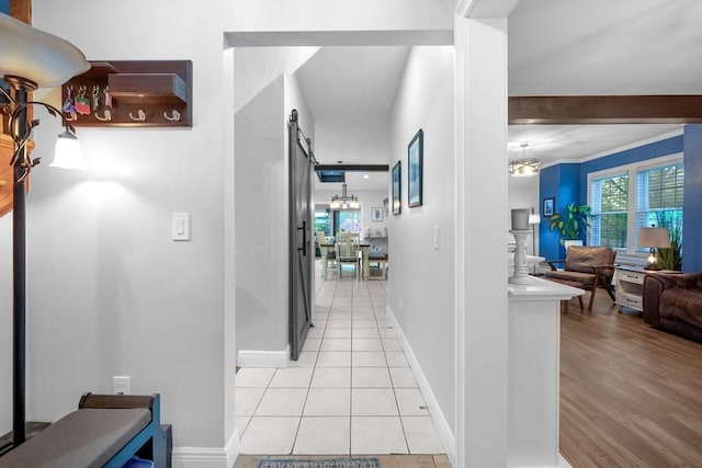 hallway with a barn door, light tile patterned flooring, and baseboards