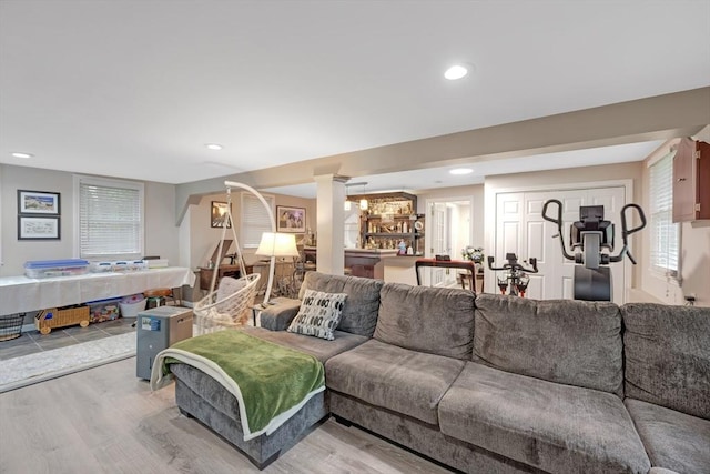 living area featuring decorative columns, light wood finished floors, and recessed lighting