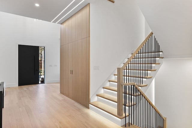 stairs with wood-type flooring and a high ceiling