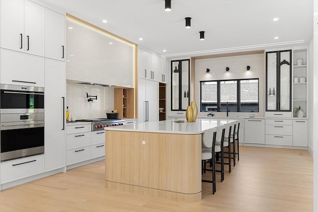 936 Central Ave, Needham, MA 02492 - kitchen featuring modern cabinets, appliances with stainless steel finishes, a kitchen breakfast bar, light wood-type flooring, and recessed lighting