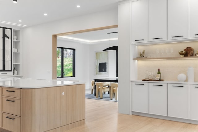 kitchen with white cabinetry, light brown cabinets, backsplash, and light wood-type flooring