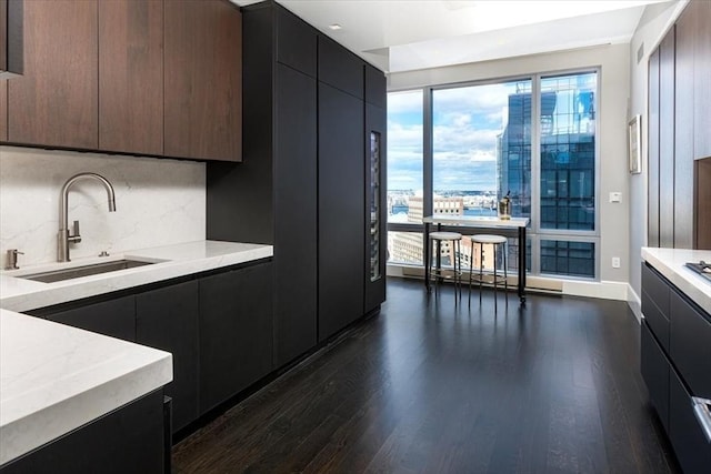 kitchen featuring dark wood-type flooring, modern cabinets, a sink, light countertops, and decorative backsplash