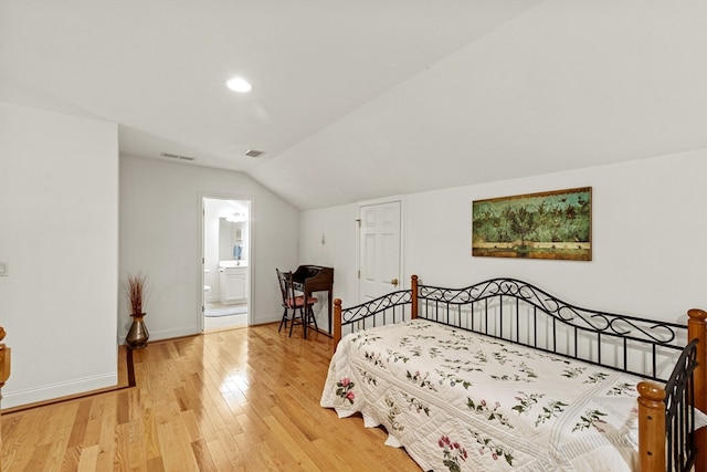 bedroom featuring ensuite bath, light hardwood / wood-style flooring, and vaulted ceiling