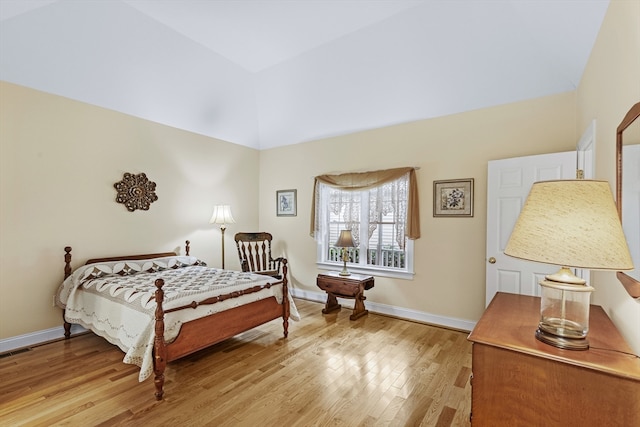 bedroom featuring light wood-type flooring and high vaulted ceiling