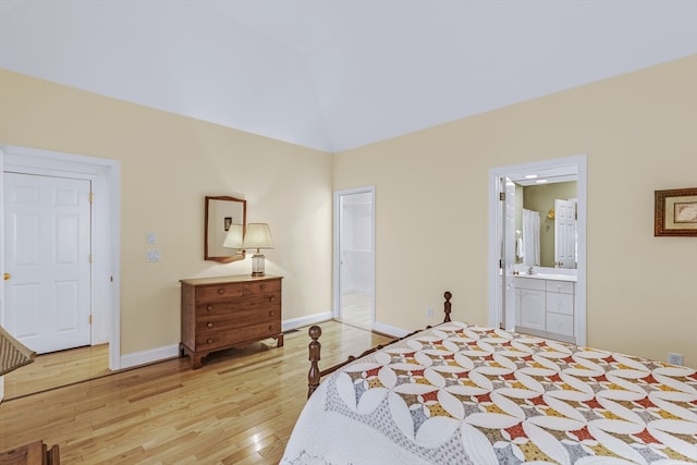 bedroom with ensuite bath, a closet, light hardwood / wood-style flooring, and vaulted ceiling