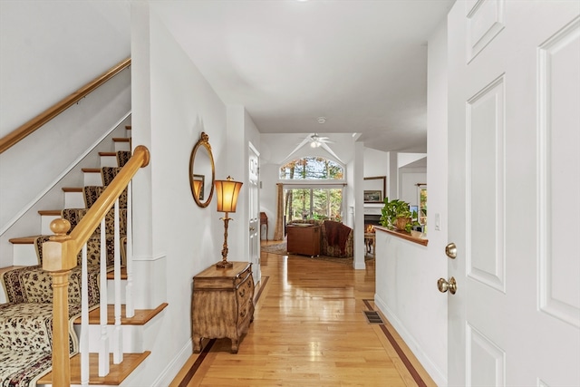 foyer with vaulted ceiling, ceiling fan, and light hardwood / wood-style flooring