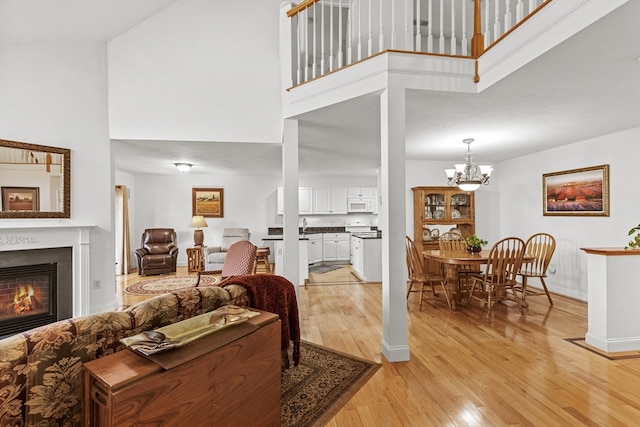 living room featuring a towering ceiling, a chandelier, and light hardwood / wood-style floors