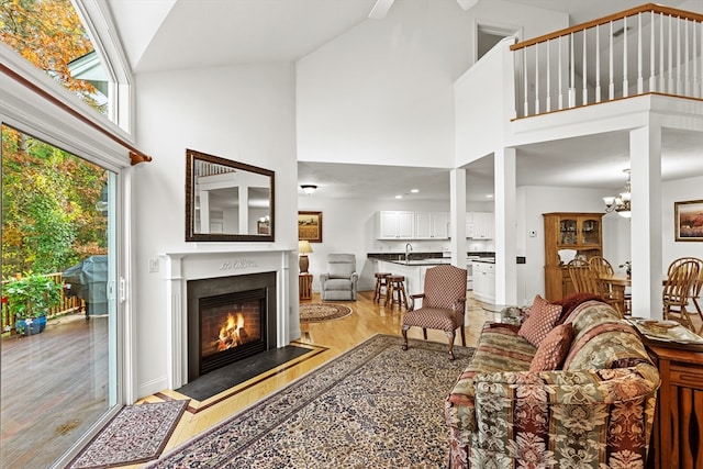 living room with light hardwood / wood-style floors, sink, high vaulted ceiling, and a notable chandelier