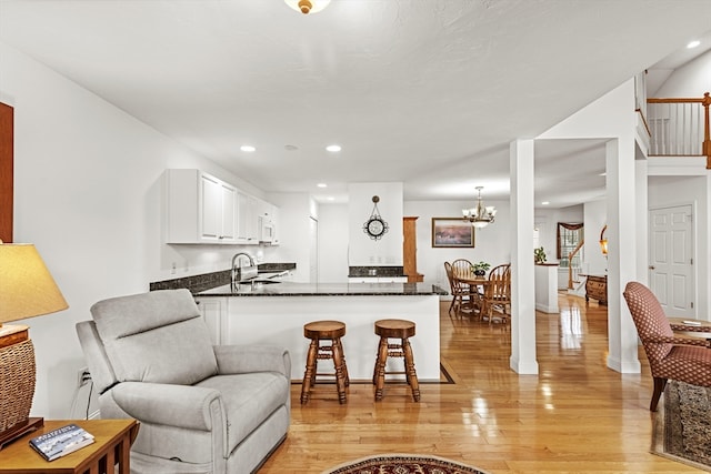 living room featuring light hardwood / wood-style floors, a notable chandelier, and sink