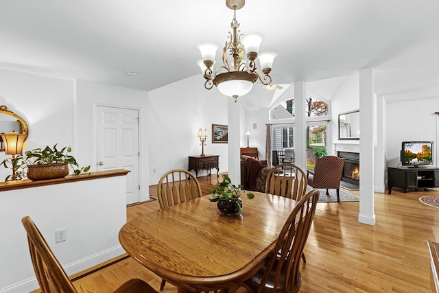 dining room with a chandelier, light wood-type flooring, and vaulted ceiling