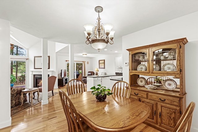 dining room with light hardwood / wood-style flooring, lofted ceiling, and a chandelier